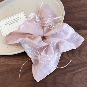 Close-up of pink lace scrunchie featuring delicate ribbon bows and floral embroidery