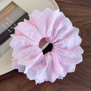Close-up of pink lace scrunchie with intricate floral embroidery and scalloped edges