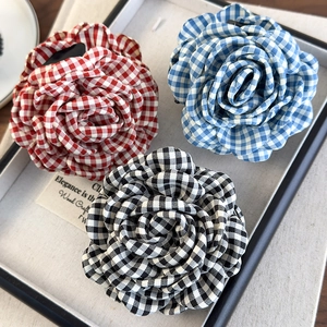 Detailed view of three vintage gingham fabric rose hair claws in red, blue, and black colors