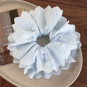 Detailed close-up of light blue floral embroidery scrunchie with scalloped lace edge