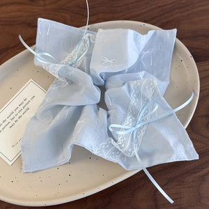 Detail of light blue lace scrunchie with ribbon bow on a decorative oval tray