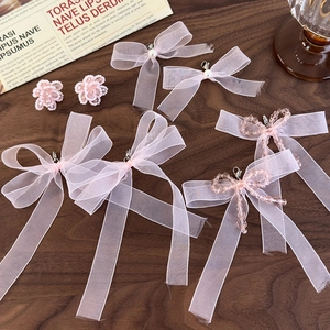 Pink ribbon bow shoe charms and crystal beaded ornaments on a vintage wooden surface