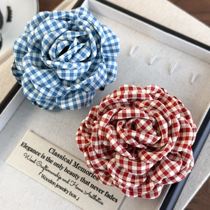 Detailed view of red and blue checkered fabric rose hair claws in a jewelry display box