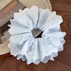Close-up of light blue lace scrunchie with floral embroidery on white ceramic tray