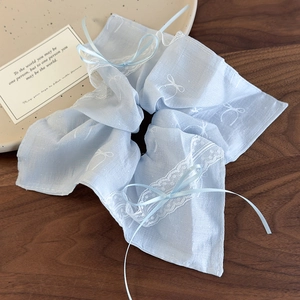 Detail of light blue lace scrunchie with ribbon bows on a dark wooden texture