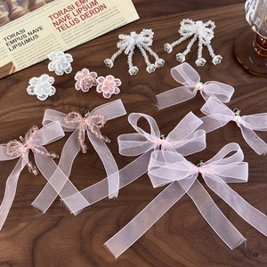 Detail view of pink organza bow and beaded floral charms with pearls on dark wood