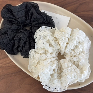 Detail of tiered lace scrunchies in black and beige on a decorative ceramic tray