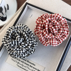 Detail view of red and black plaid camellia flower hair clips on a display tray