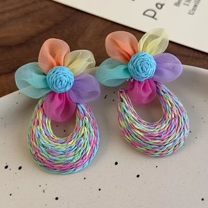 Close-up of colorful chiffon flower earrings with handcrafted raffia teardrop pendants