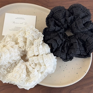 Elegant layered lace scrunchies in cream and black on a textured wooden background