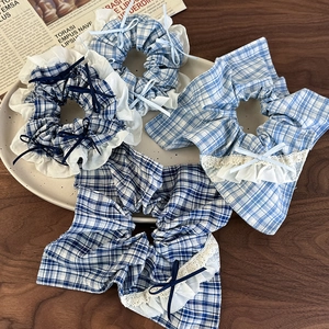 Set of four blue plaid scrunchies with lace edges and bows on a ceramic plate