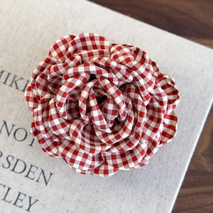 Detailed close-up of a red and white gingham fabric rose hair claw with layered petals