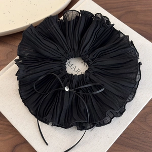 Close-up of black mesh scrunchie featuring a ribbon bow and sparkling rhinestone detail