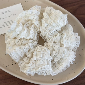 Detailed view of large layered lace scrunchie in cream on a ceramic plate