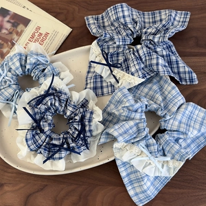 Detail of blue plaid hair scrunchie with lace trim and ribbon bow in a ceramic tray