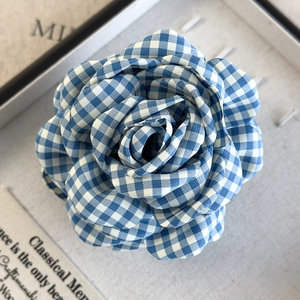 Detail of blue and white checkered fabric flower hair claw with intricate petal texture