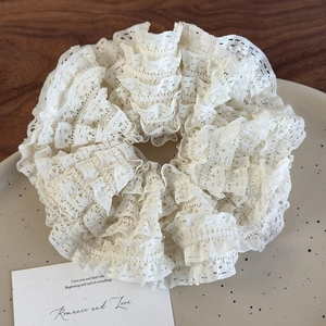 Detail shot of multi-layered lace scrunchie with layered ruffle texture in cream white