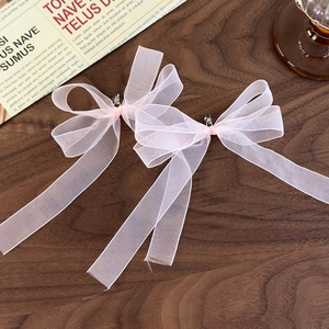 Detail of pink organza ribbon bows with decorative bells on a vintage background