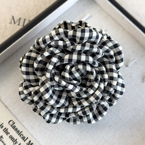 Macro shot of black and white plaid fabric camellia flower hair clip on jewelry stand