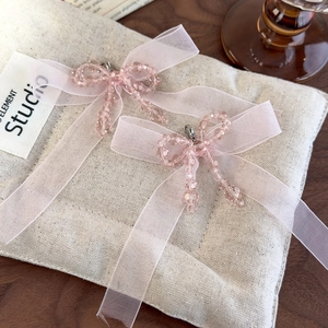 Macro detail of pink crystal beaded bows and organza ribbons on textured linen mat