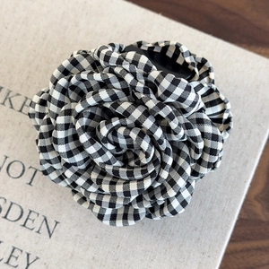 Close-up of a checkered camellia flower hair claw clip with black and white fabric petals