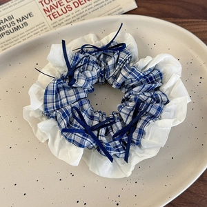Detail of blue plaid hair scrunchie with white lace edges and dainty dark blue bows