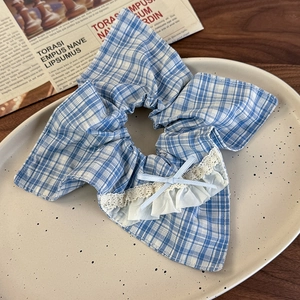 Detail of blue plaid hair scrunchie with lace trim and bow on a ceramic plate