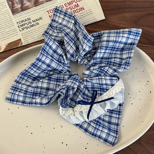 Detail of blue plaid hair scrunchie with white lace trim and dark blue bow decoration