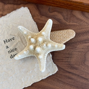 Detail shot of a natural starfish hair clip with woven straw texture on a wooden desk