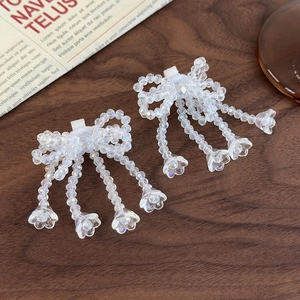 Detail view of handmade crystal beaded bow shoe charms with hanging floral tassels