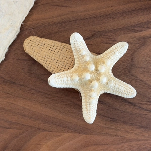 Detailed close-up of a starfish hair clip with woven texture on a dark wood background