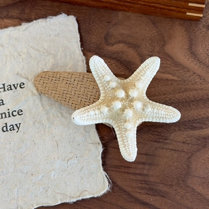 Detail of natural starfish hair clip with woven texture base on rustic wood background