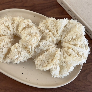 Vue détaillée de deux chouchous en dentelle blanc crème avec pétales 3D sur un plat céramique