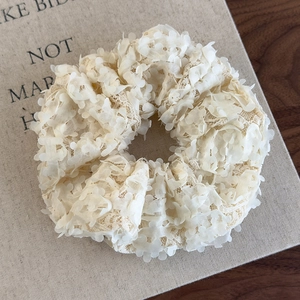 Détail d'un chouchou floral blanc crème avec pétales 3D et textures de dentelle