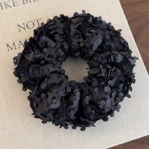 Vue détaillée du chouchou noir à pétales 3D avec texture en maille et détails en dentelle