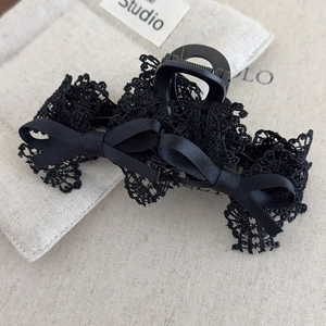 Detailed macro view of black lace bow hair claw clip with satin ribbons and matte finish
