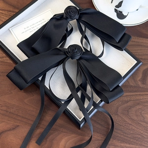 Close-up of elegant black satin bow hair clips with rose detail on a vintage tray