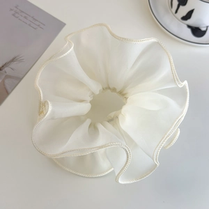 Detailed macro view of large cream organza scrunchie with layered ruffle edges
