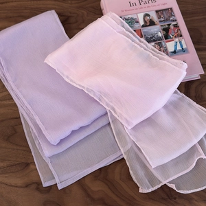 Elegant light purple and pink sheer scarves in soft texture on a wooden table surface