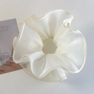 Detail of a large cream-colored tulle hair scrunchie with delicate ruffled wavy edges