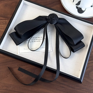 Elegant black satin bow hair clip with camellia flower and long flowing ribbon streamers