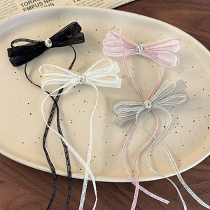 Detail of four tulle bow hair clips with crystal accents and long ribbons on a ceramic plate