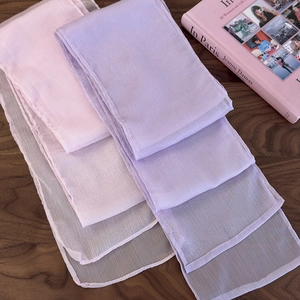Detailed texture of lightweight pleated scarves in soft Morandi colors on dark wood