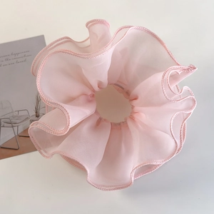 Detail of light pink layered mesh organza scrunchie with ruffled edges and soft texture
