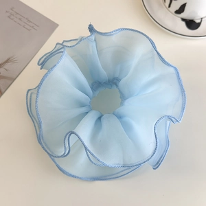 Close-up of light blue double-layered tulle scrunchie with ruffled organza edge textures