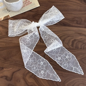 Détail d'un ruban à cheveux en dentelle blanche avec motifs floraux et broderie