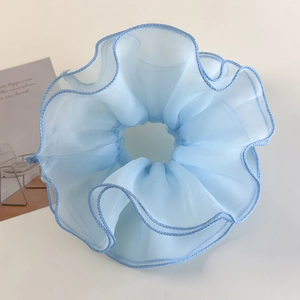 Detailed close-up of a light blue layered tulle scrunchie with delicate ruffled edges