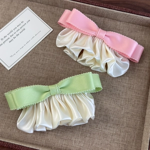 Detail von rosa und grünen Satin-Haarspangen mit plissierten Kanten in einem Tablett