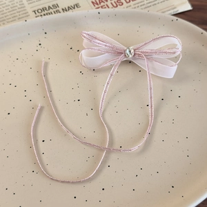 Detail of pink mesh ribbon hair clip with sparkling crystal center on ceramic tray