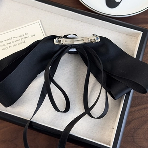 Close-up of the silver metal spring clip on a vintage black satin ribbon bow